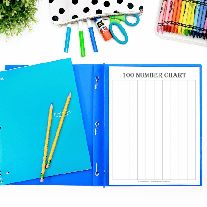 free 100 number chart printable Blank 100 number chart printable placed inside a blue binder with pencils, crayons, scissors, and school supplies nearby. The page is titled "100 NUMBER CHART" and features an empty ten by ten grid for filling in numbers.