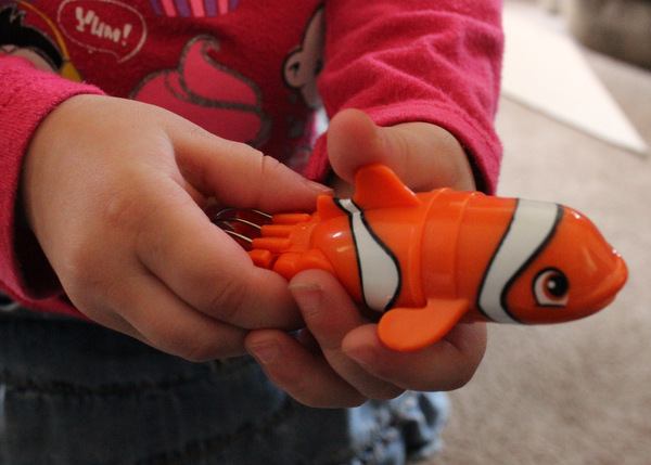 Child's hands holding Lil' Fishys motorized fish toy