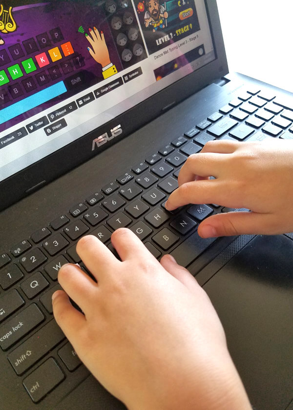 Close-up view of child's hands typing on laptop