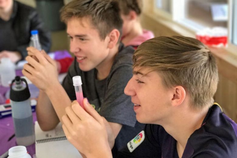 2 teen boys observing test tubes in science lab