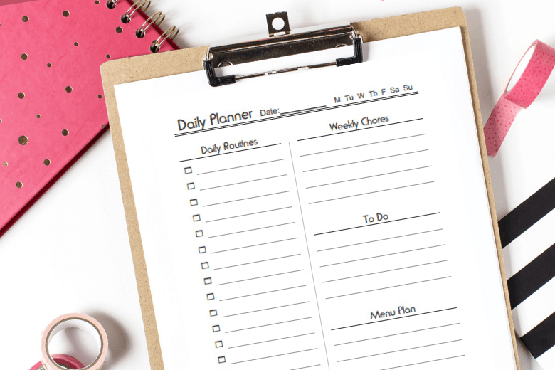 Planner printable on clipboard surrounded by pink desk accessories