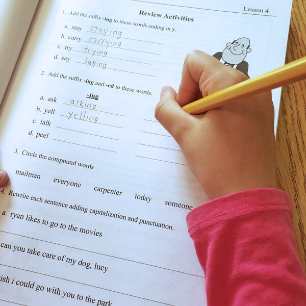Girl's hand writing with pencil on a language arts worksheet