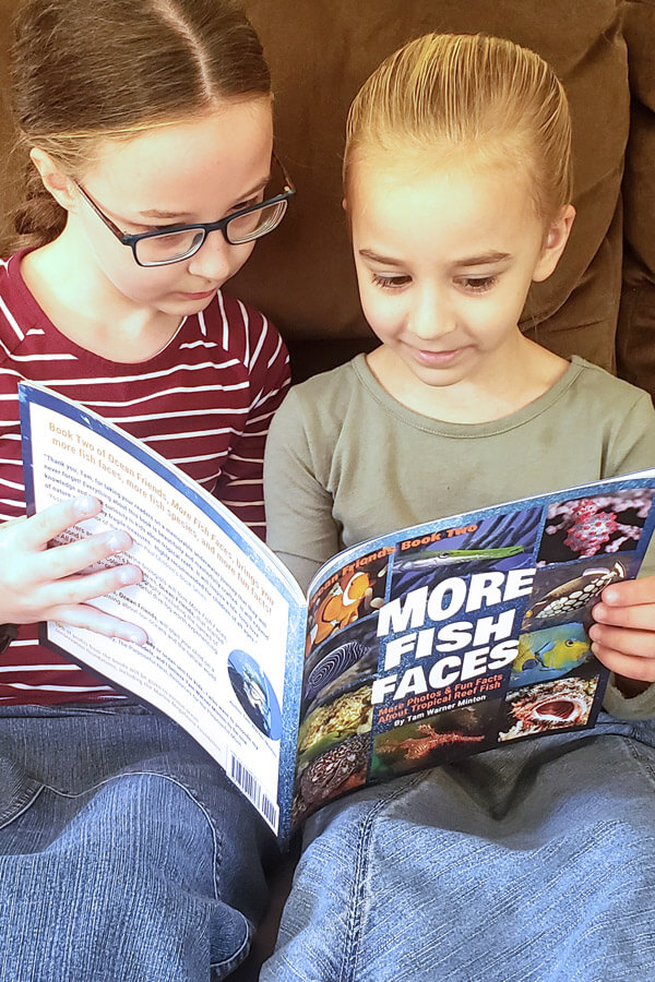 Two young girls looking at a colorful children's book together