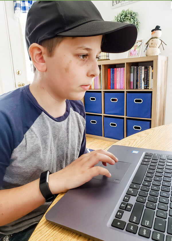 Middle school boy doing homeschool math problems on laptop