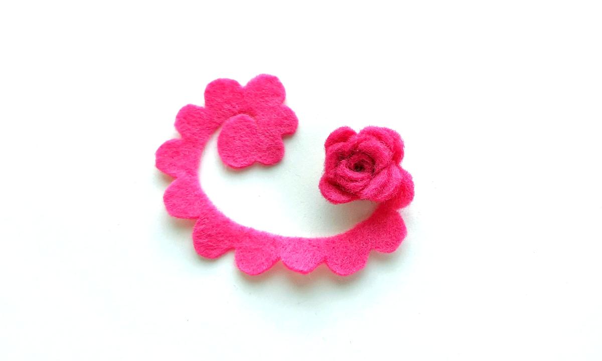 Image of bright pink felt cut into a spiral shape and partially rolled up on white background