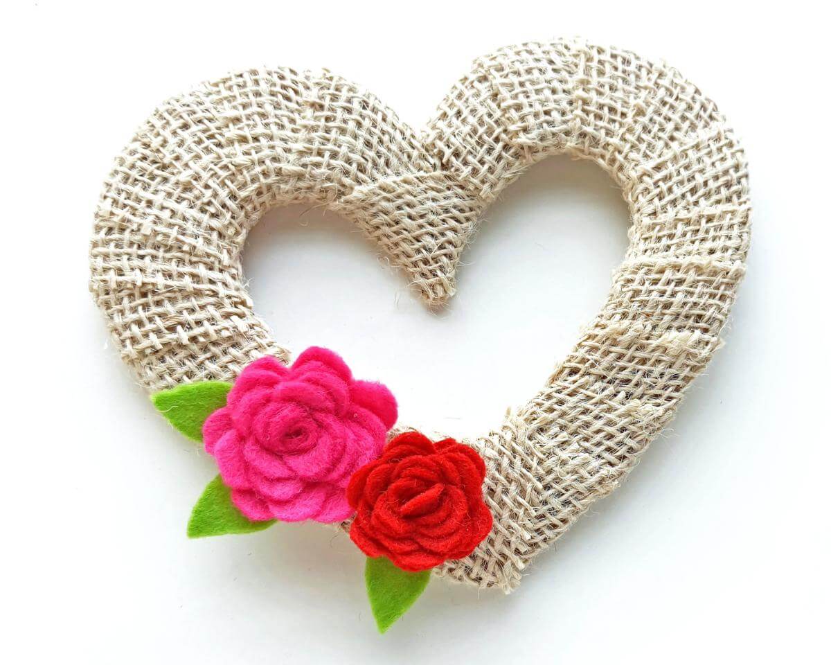 Image of heart-shaped wreath covered with tan burlap with a red rose and a bright pink rose on the lower left edge