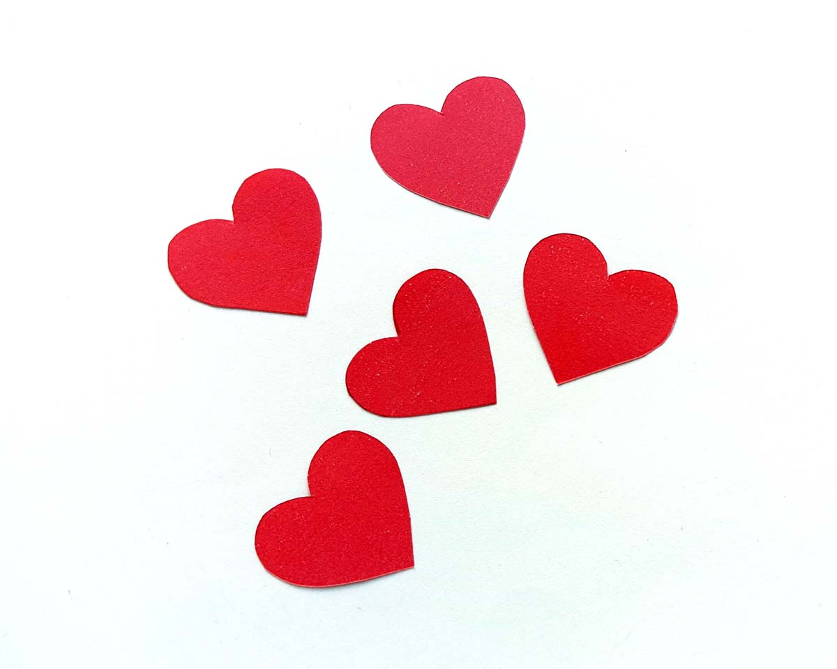 Image of five red paper hearts lying on a white background