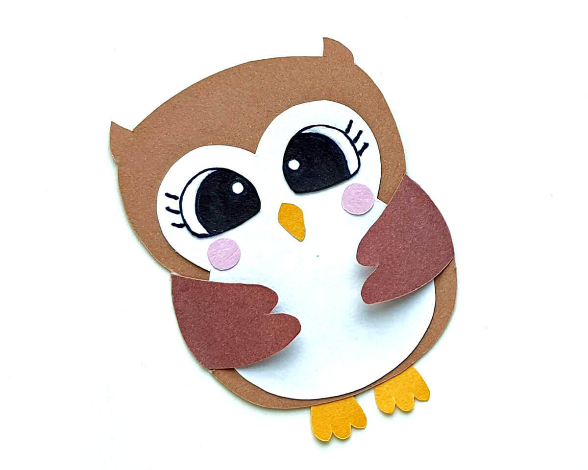An almost completed brown paper owl lying on a white background