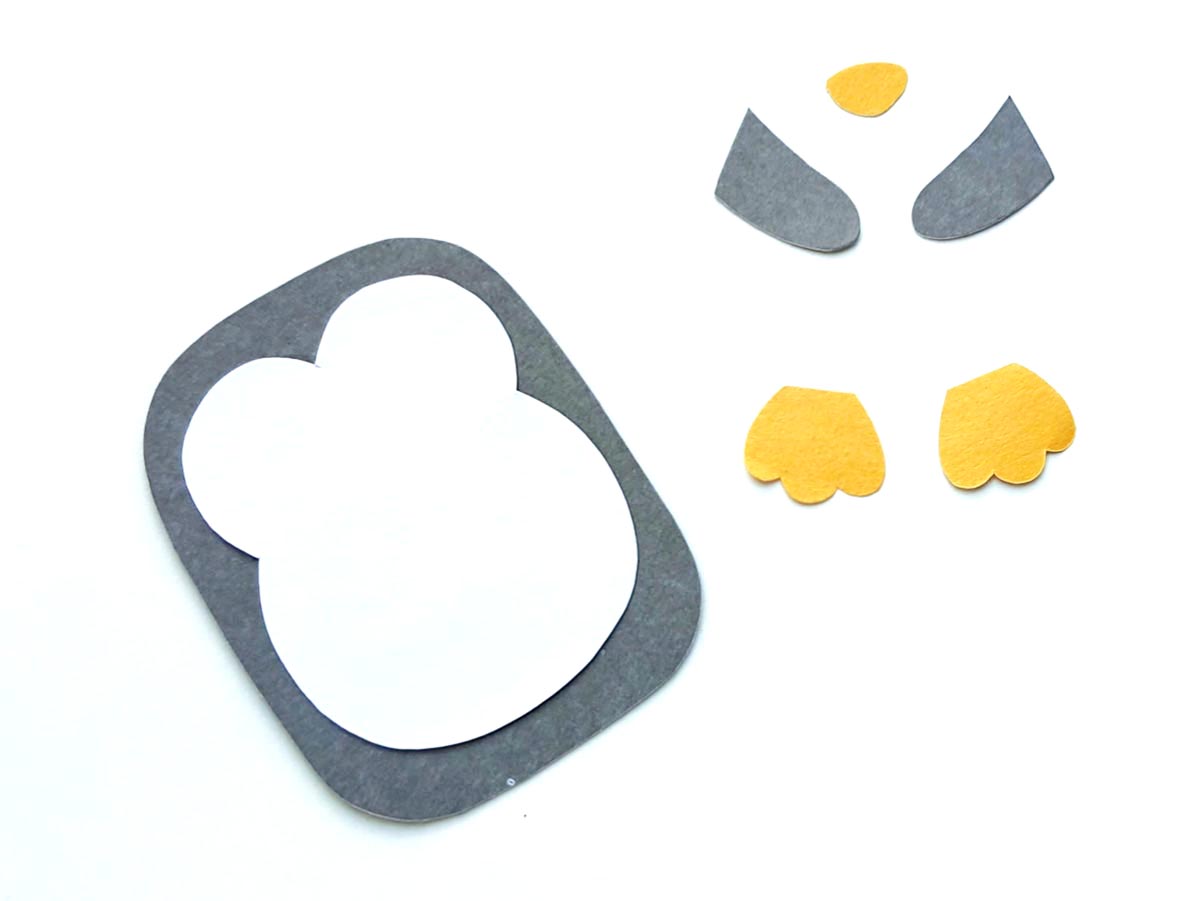 Image of gray, white, and orange paper shapes being assembled to make penguin paper craft