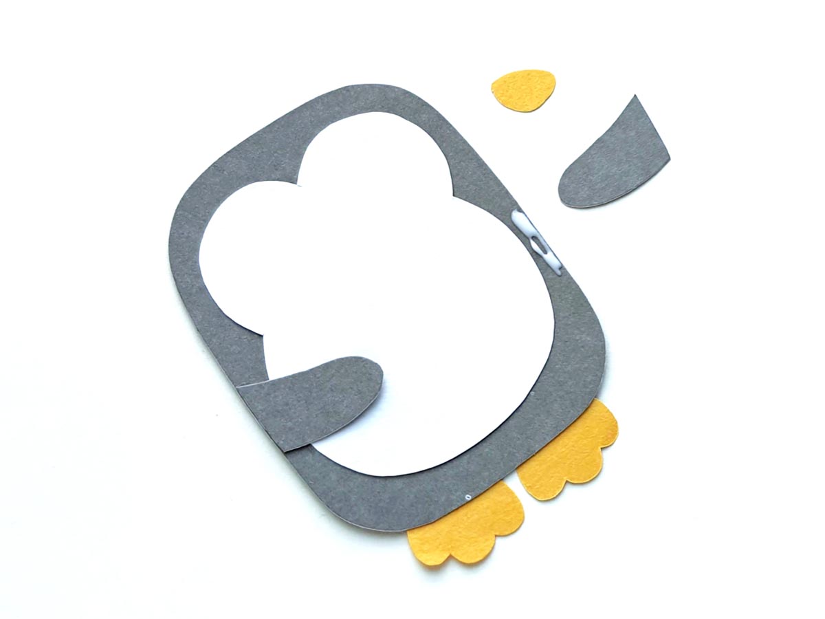 Image of partially assembled paper craft penguin lying on white background