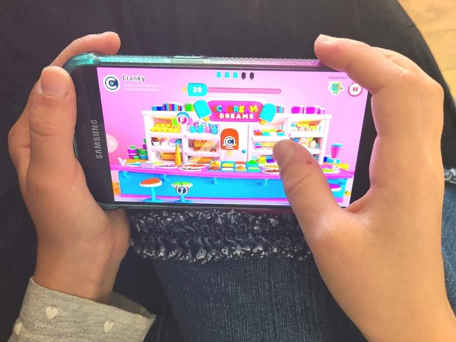 Image of child's hands holding a smartphone and playing a social emotional learning game