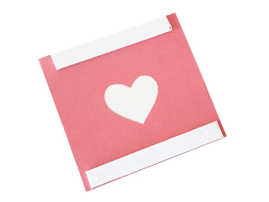 Image of a pink square of paper with a small heart cut out of the center.