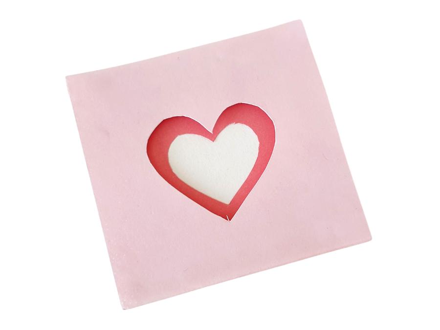 Image of 2 shades of pink paper stacked together, with hearts cut out from the center to make a 3D shape.