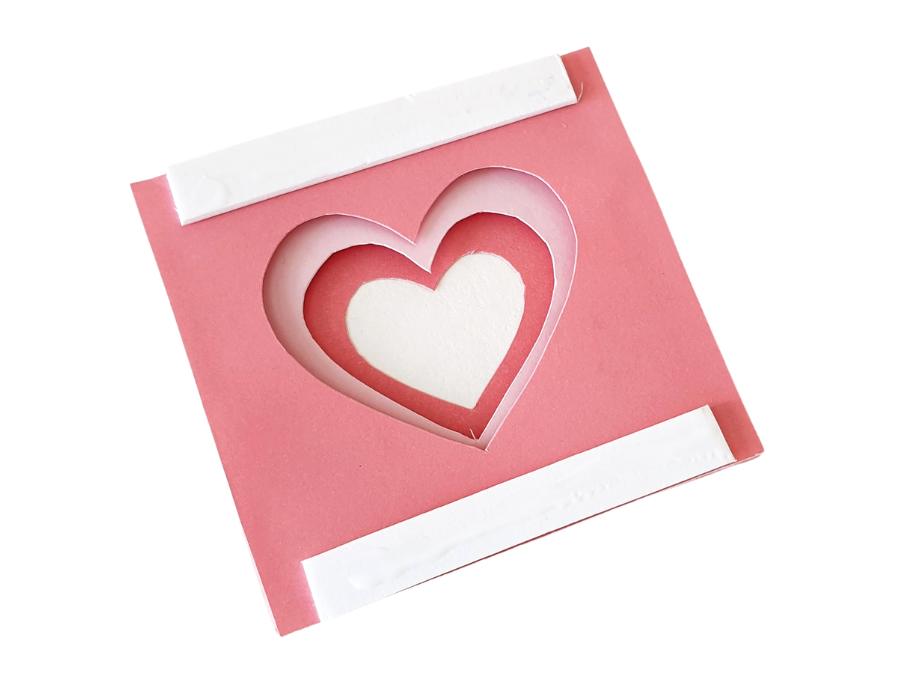 Image of a partially assembled 3D heart papercraft in shades of pink on a white background.