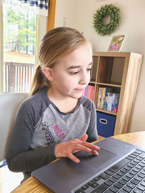 Image of young girl in gray shirt using a laptop for homeschool lessons