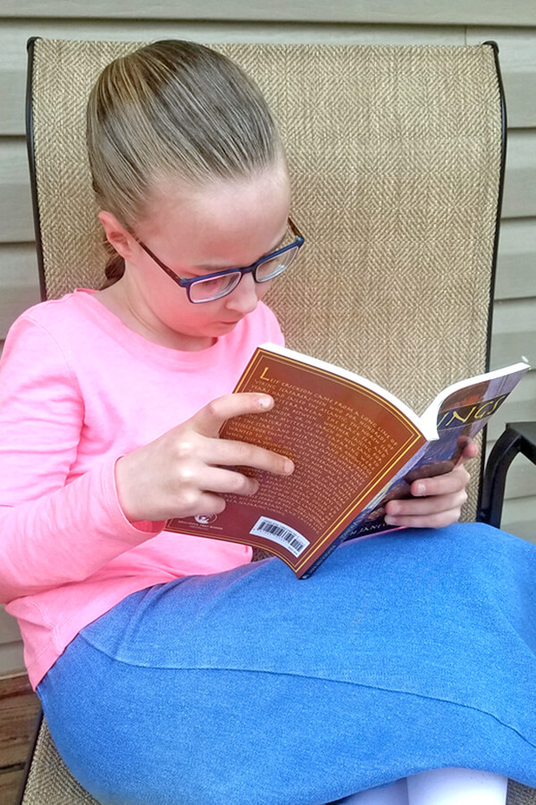 Image of young girl sitting in chair reading a homeschool history book about the Vikings.