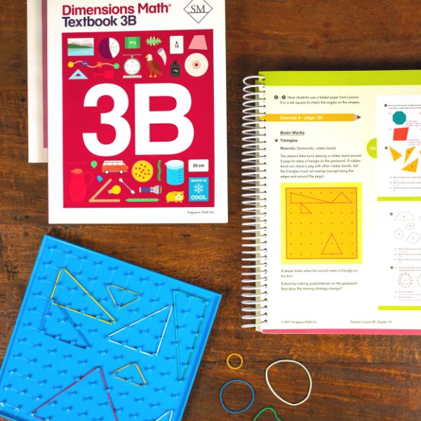 Image of a Dimensions Math textbook and a geoboard on a wood table.