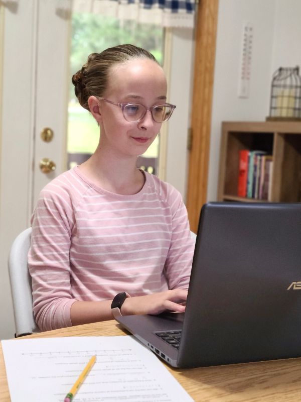 Image of smiling girl using laptop to work on a Mr. D Math class.