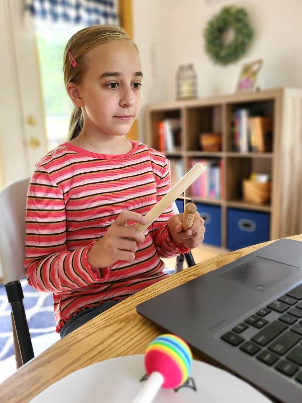 Elementary music lessons for homeschool Image of middle school girl using rhythm sticks during an online music lesson.