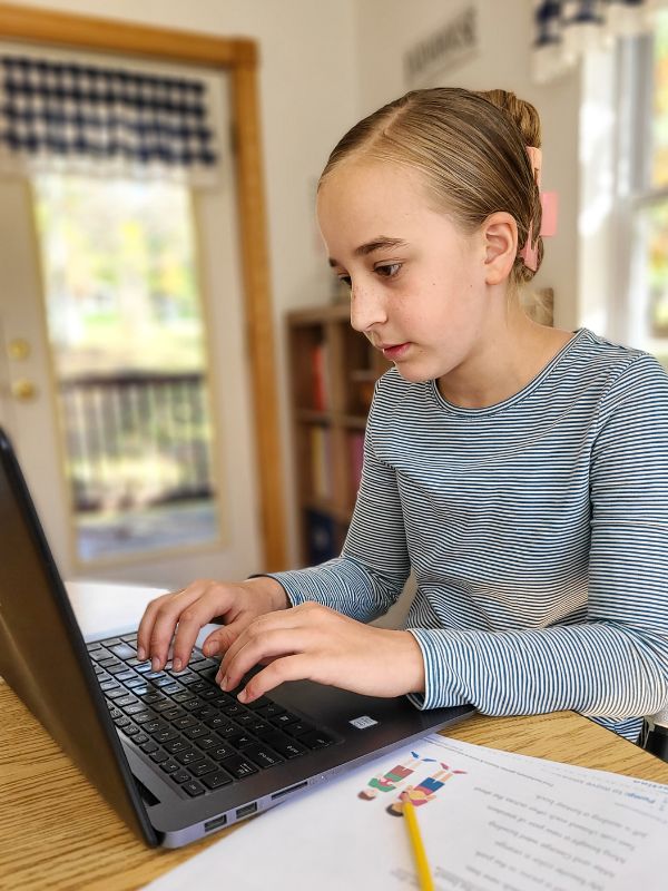 Image of elementary school girl using a laptop for educational games and lessons.