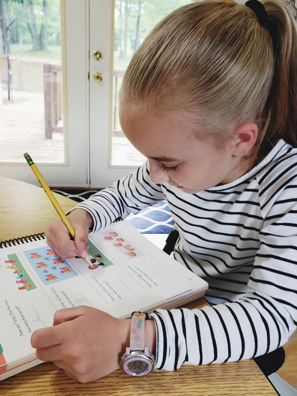 Christian math curriculum Image of young girl writing in a math workbook.