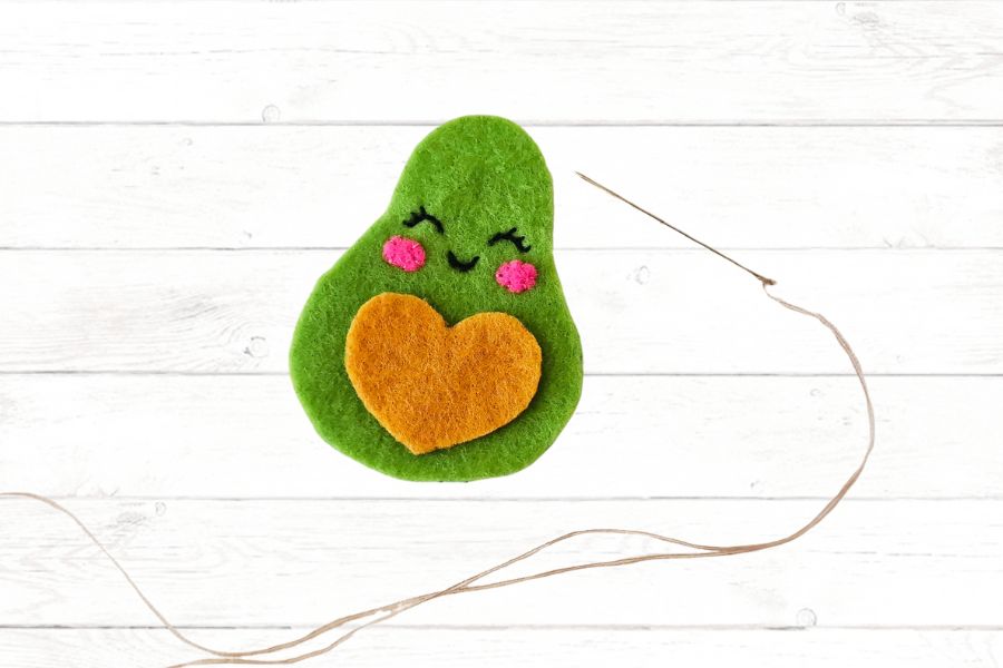 Sewing project for kids Image of green felt avocado with a needle lying beside it to stitch pieces together.