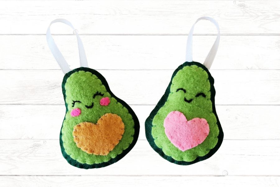 How to make an avocado stuffie Image of two cute stuffed avocados with stitched faces.