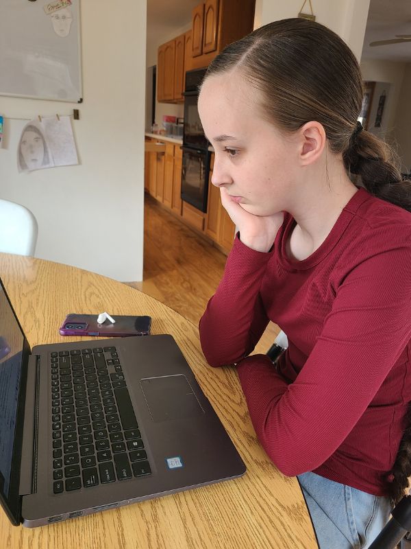 Online blockchain course for teens Image of teen girl watching an online cryptocurrency course on a laptop.